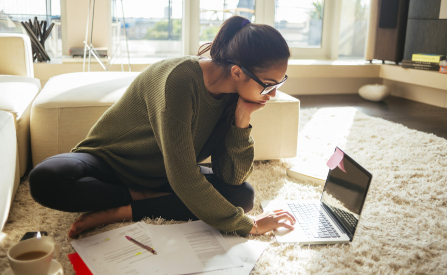 Dark haired woman with glasses working on her comuputer 